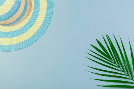 在海滩上俯视配件绿松石蓝色背景条纹蓝色帽子和棕榈叶。概念海滩度假，海上旅游，温暖阳光明媚的夏天。广告空间