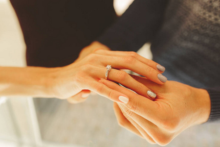 图为男女手拿结婚戒指,新婚夫妇在珠宝店选购结婚戒指.照片