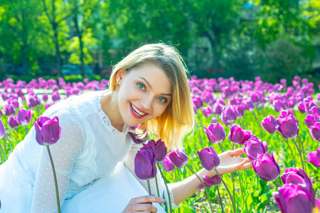 妇女节，3月8日。在郁金香地里放松的年轻女子。花园里开着郁金香花的美女。