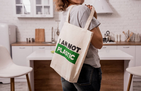 Young girl holding a cloth bag. At the kitchen. I am not plastic