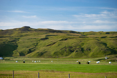  stacks of grass on green field with beautiful green hills and s