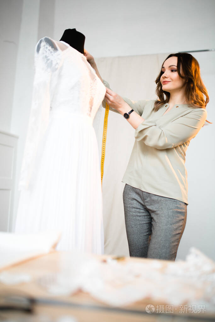 裁缝在缝纫店的人体模特上量衣服