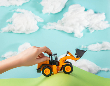 一个小孩玩着一辆开过纸丘的玩具卡车.照片