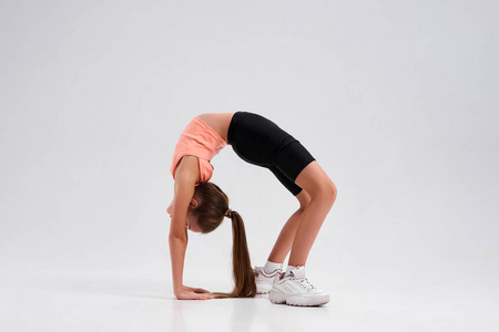 柔韧可爱的小女孩在白色背景下孤立地伸展身体,向后弯腰.