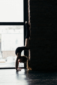 体操运动员正站在她的怀里。一个女孩的剪影在明亮的窗户背景上。
