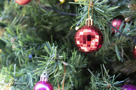 圣诞装饰特写。在假松树上挂装饰品。上面有彩色的球。