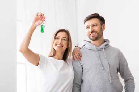 Embracing smiling couple looking at keys of new home