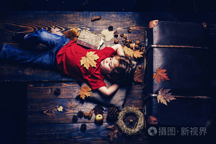 玩落叶的小孩孩子在玩秋天金发秋叶时节小男孩趴在木地板上休息秋季