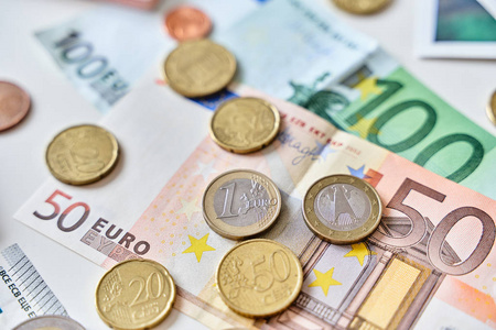 一个欧元硬币的特写镜头被不同的硬币和100欧元和50欧元包围