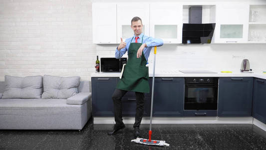  handsome man in tie and apron mops the floor in the kitchen
