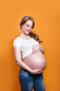 漂亮的女人怀着孩子，抚摸着她的肚子。怀孕
