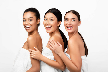 三个快乐的女人在白色背景下用浴巾摆姿势