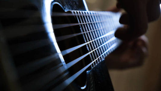 男人在家里弹吉他，手特写。概念。一个人弹吉他的特写镜头