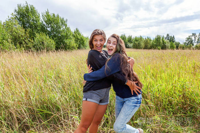 两个女孩朋友在户外拥抱跳舞,一起享受大自然的乐趣.