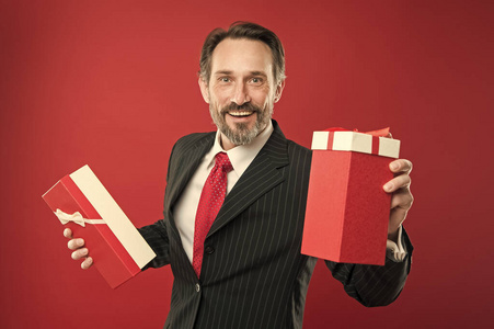 为你。快乐的商人赠送红色背景礼物。成熟的男人带着礼物微笑。生日礼物。节礼日。礼品包装。把你的礼物包起来。欢迎来到假日