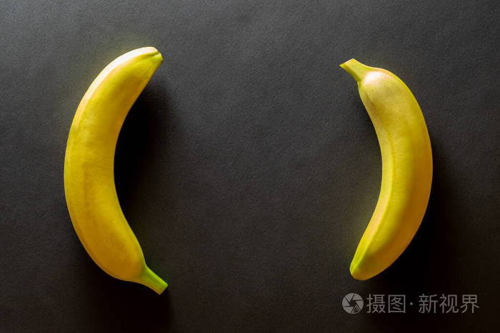 黄色背景设计。香蕉被隔离在黑色和复制空间。从上面看。