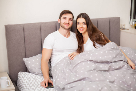 快乐的性感的年轻夫妇躺在床上。