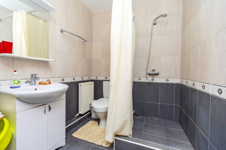 客房内的淋浴房。上面是米色的瓷砖，下面是深色的瓷砖。淋浴和水槽