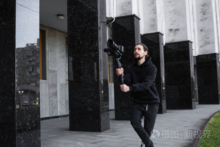年轻的专业摄像师在3轴万向节稳定器上手持专业摄像机专业设备有助于