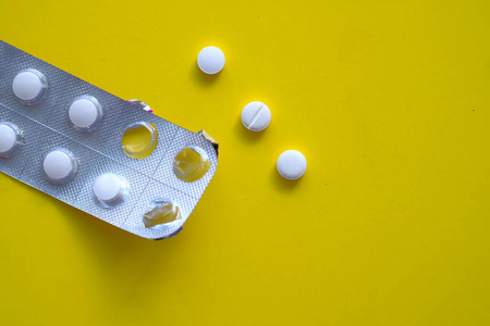 close up of white pills on yellow background 