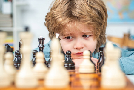 可爱的小男孩在下棋。有思想的孩子。全神贯注的男孩发展象棋策略，玩棋盘游戏。