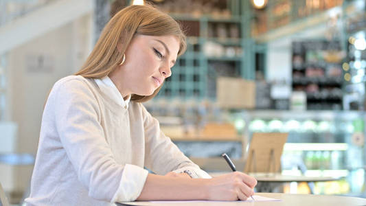 严肃的年轻女人在咖啡馆做文书工作
