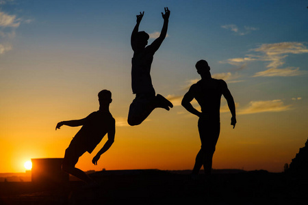 Group Of Happy Young People Jumping On The roof with sunset on b