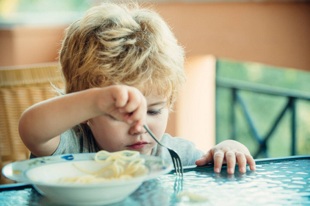 孩子和食物。孩子们的胃口。婴儿在餐桌上吃意大利面。