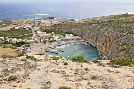可以俯瞰内海，旁边是小房子，背景是马耳他戈佐的真菌岩。
