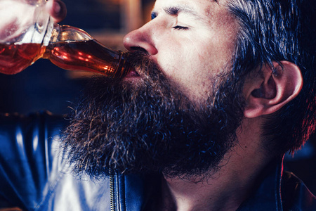 醉汉.大胡子男人喝威士忌,白兰地或白兰地.室内复古酒吧.
