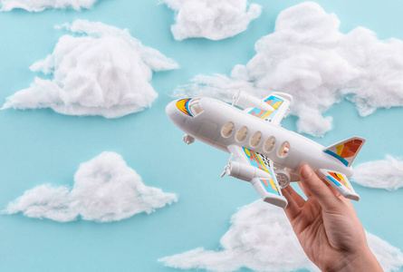 儿童手上的白色飞机玩具在手工制作的天空中飞翔