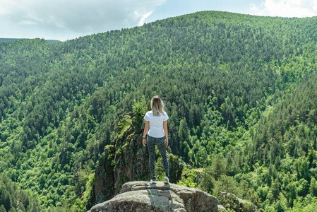 一个漂亮的小女孩站在山上看森林