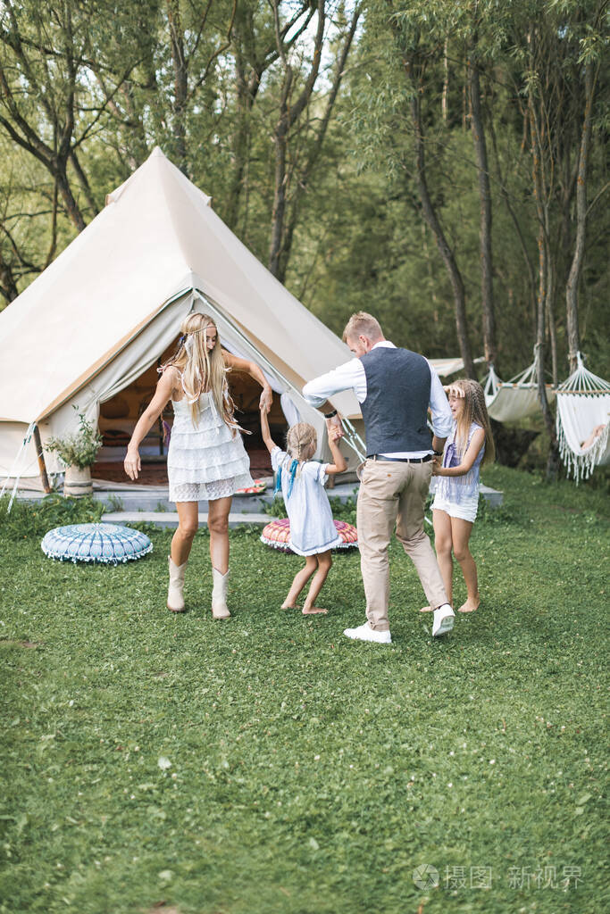 一起跳舞户外野营野餐快乐的一家人穿着便装手牵着手在草地上绕圈子