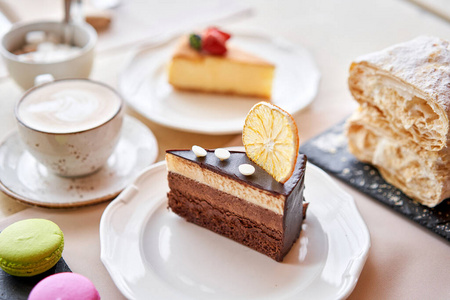 卡布奇诺和很多甜点在桌上.拿破仑,巧克力蛋糕,芝士蛋糕和杏仁饼.照片