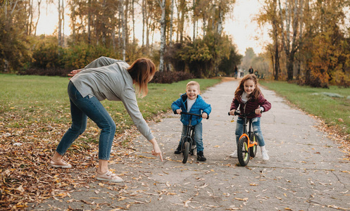 白人母亲和孩子们在公园里骑着自行车散步