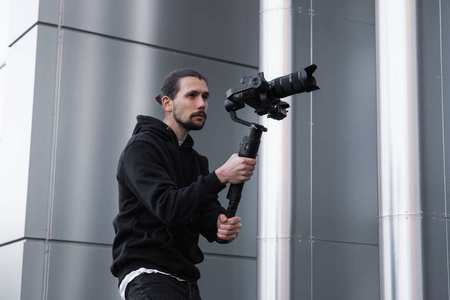 年轻的专业摄像师在3轴万向节稳定器上手持专业摄像机.