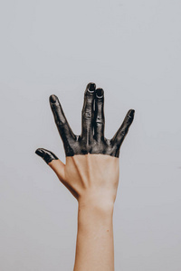 Elegant female hand dipped in black paint on a light background.