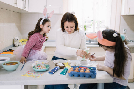 小女孩戴着兔子耳朵和妈妈准备画鸡蛋