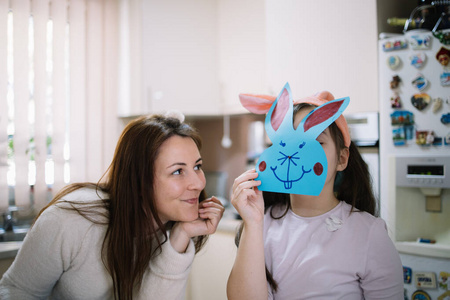 快乐的妈妈看着她脸上蒙着兔子的孩子
