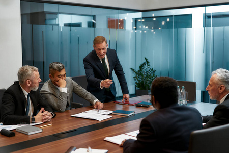 在一个正式的会议室里,当一个成熟的商人和同事们在会议室里愤怒的