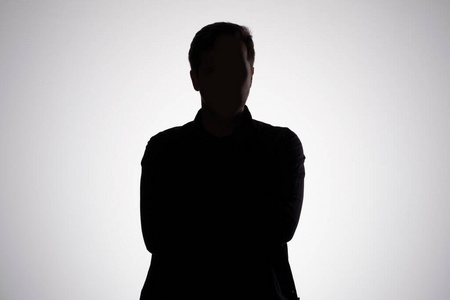 命名的戏剧灰色工作室墙上的男人剪影.摄影棚镜头照片