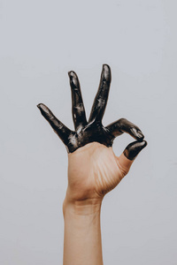 Elegant female hand dipped in black paint on a light background.