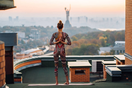 在大城市的摩天大楼屋顶上做瑜伽的女人。
