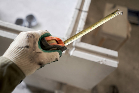 建筑工人用卷尺测量石膏板。使用带槽脊的石膏混凝土板建造公寓内墙。企口石膏砌块