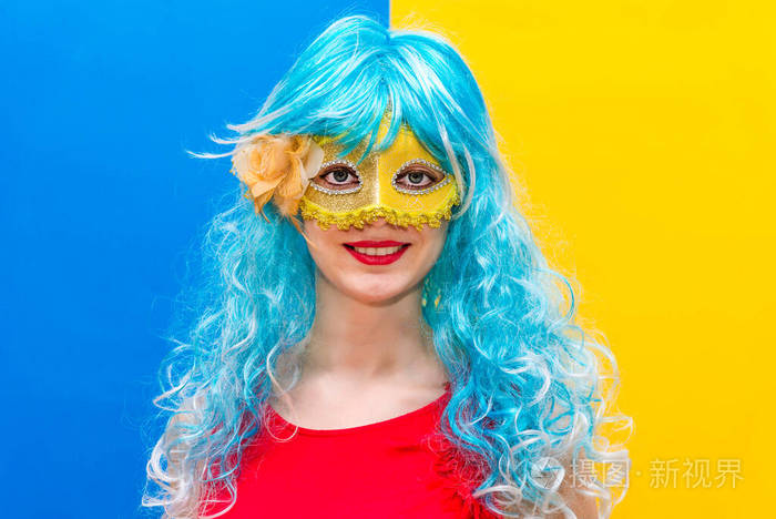一个戴着蓝色假发和黄色面具微笑的女孩将要庆祝化装舞会.