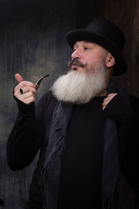 成熟帅气欧美摄影棚写真帅气成熟胡须男戴烟斗黑礼帽,选择性聚焦照片