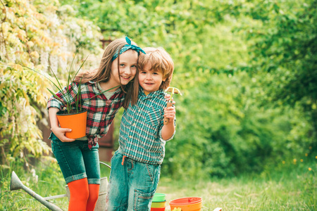 春季园艺常规。小男孩和女孩在春天的院子里园艺和玩耍。