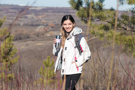 爬山的女人停下来喝一杯。女旅行者在山上用保温瓶喝茶