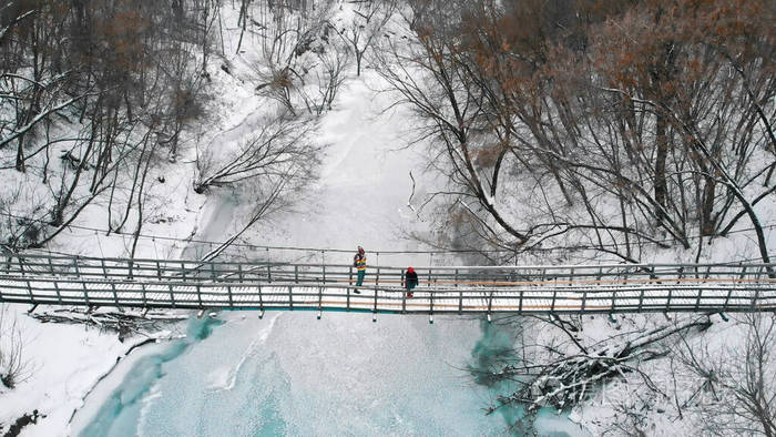 两个年轻的女人站在冬天森林里的雪桥上