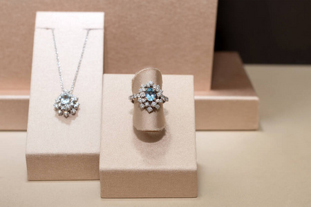 镶有蓝色宝石的钻戒和项链。展台上的白色金色戒指。时尚奢华配饰
